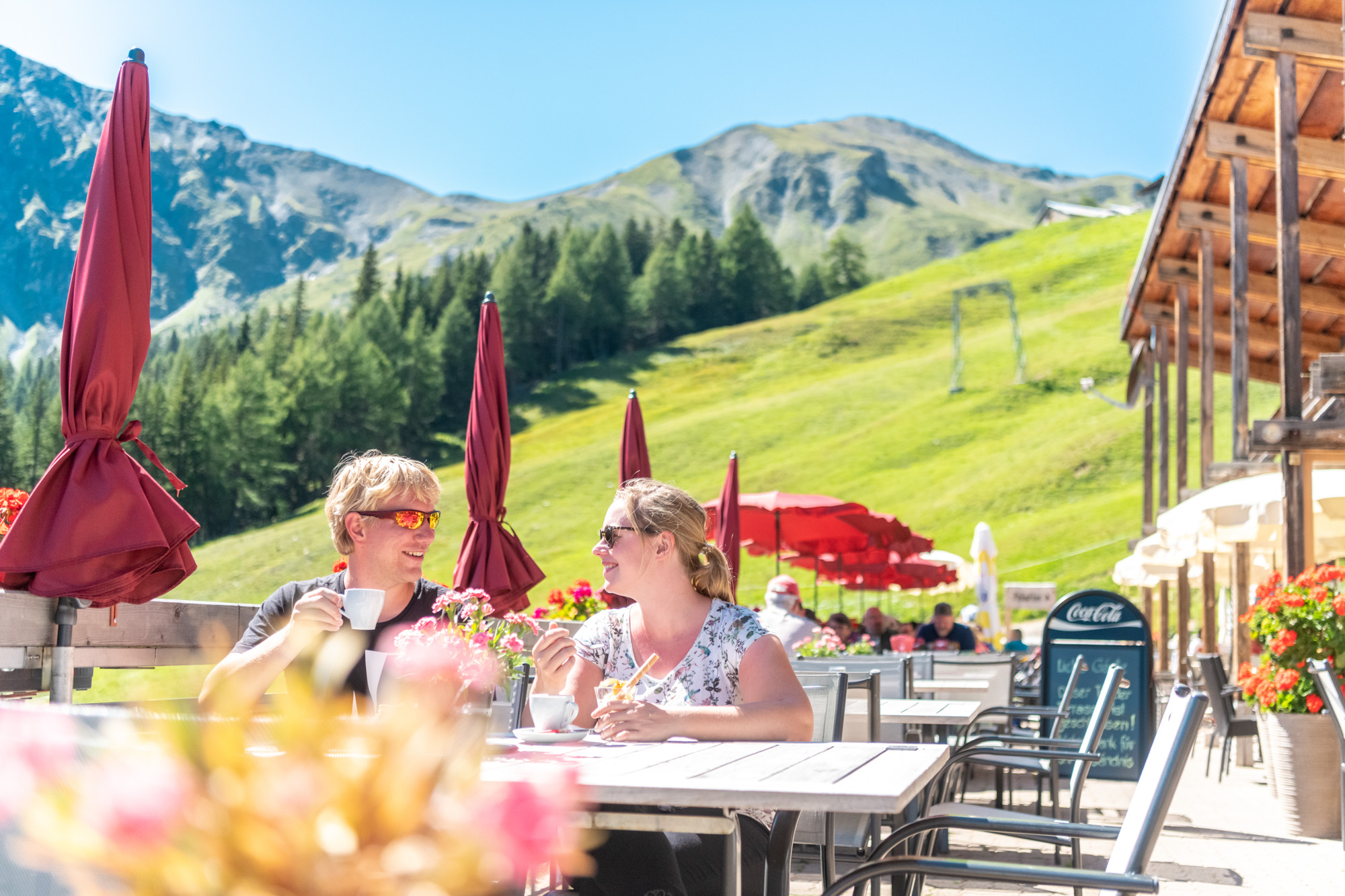 Paar geniesst Zvieri bei sonnigem Wetter im Bergrestaurant in Pradaschier